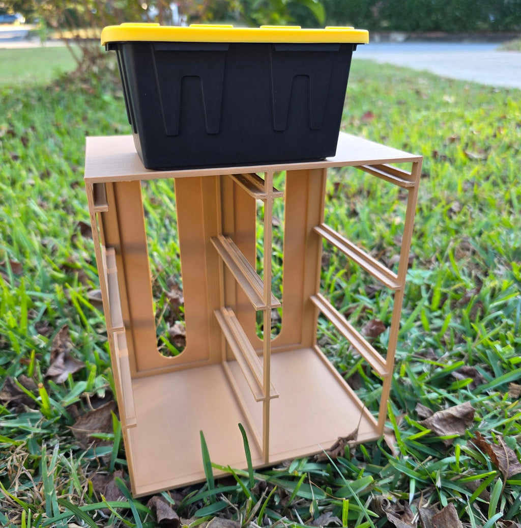 A black plastic container sits atop a beige wooden structure in a grassy area.