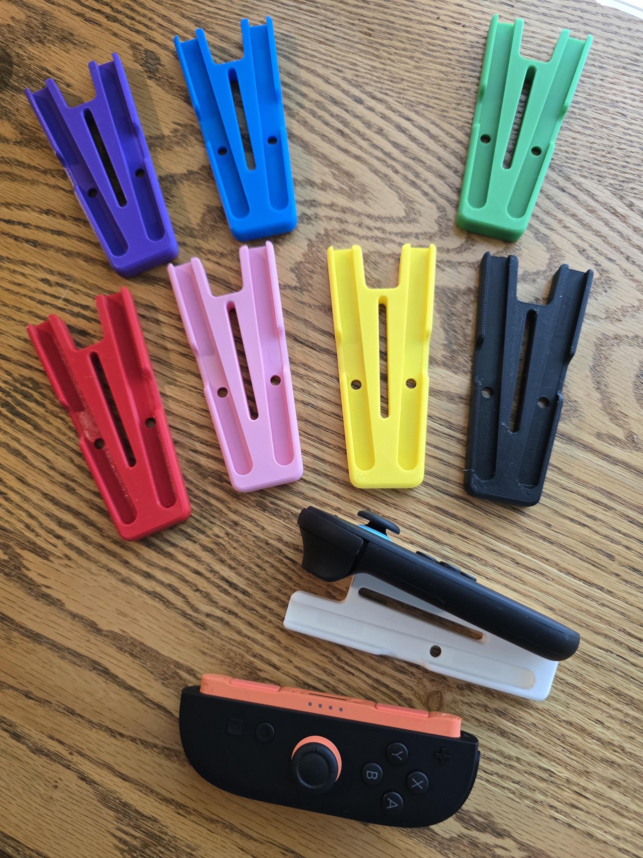 a collection of colorful plastic holders and a black and orange game controller on a wooden surface.