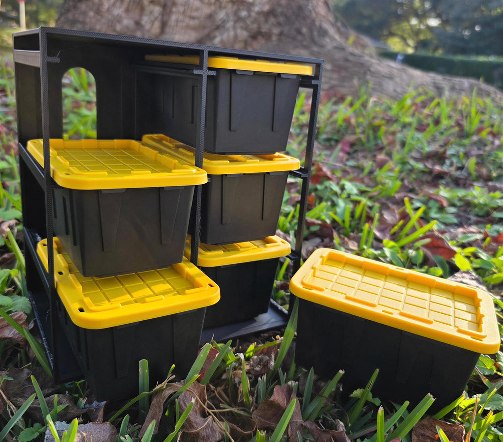 A set of black and yellow storage containers is placed on the ground in a grassy area, with a tree trunk visible in the background.