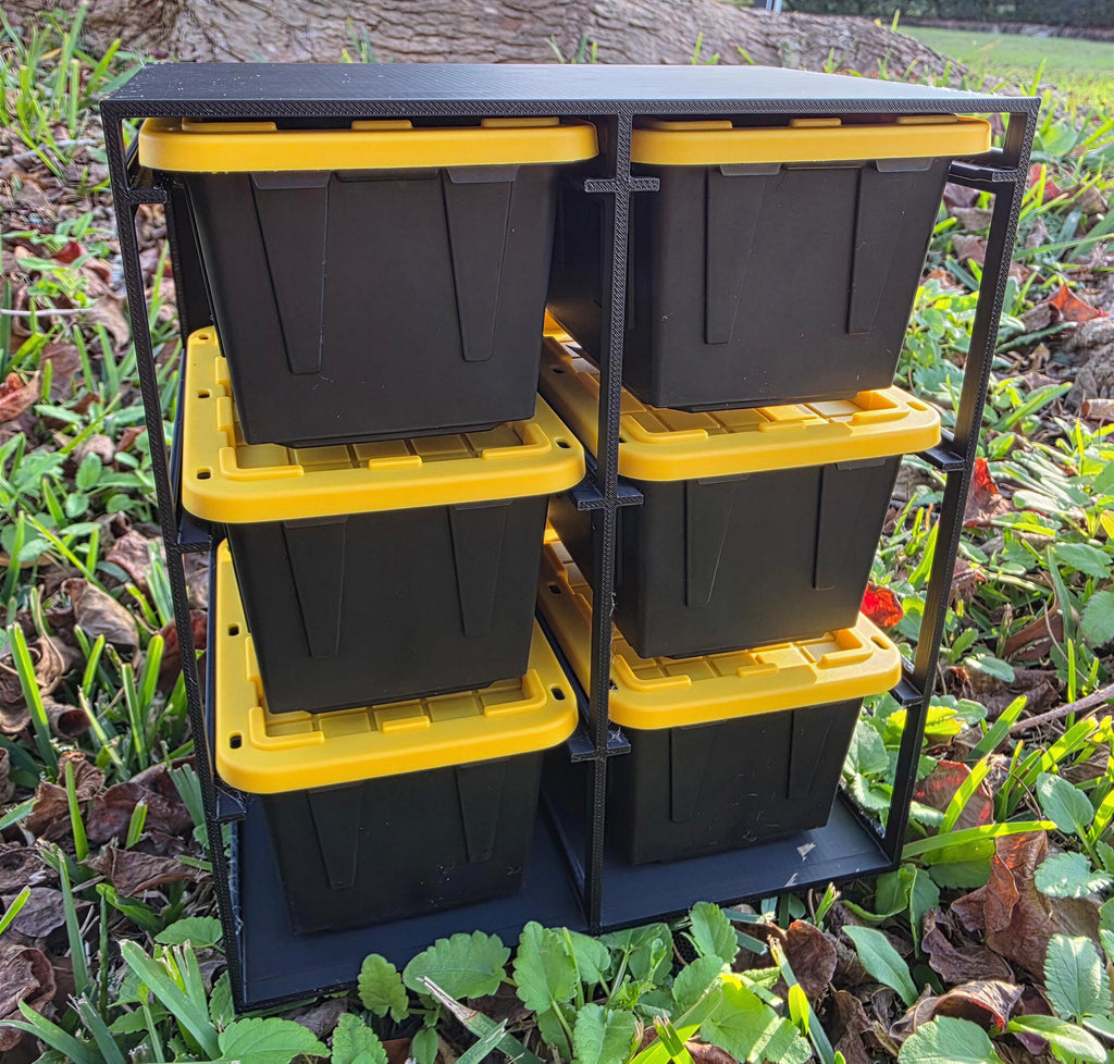 A black metal storage unit with six yellow plastic bins stacked on top of each other, placed on the ground surrounded by grass and leaves.